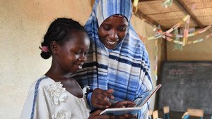 Teacher and student look at book together.