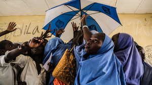 Students in a classroom in Nigeria hold up an umbrella.