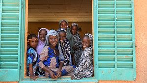 Group of girls in Niger look out a window and smile.