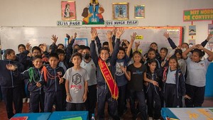 Children inside a classroom smiling and waving their hands