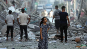Young girl in Gaza looks out amidst rubble.