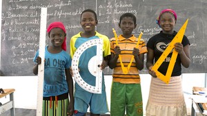 Children inside a classroom holding school supplies