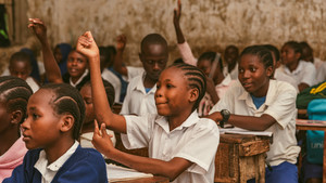 Girl in class in Kenya raises hand.
