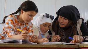 Teacher working with two students in Syria.