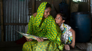 Mother reading a book to her daughter in Bangladesh