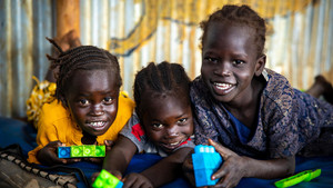 Children playing with didactic materials smiling and looking at the camera