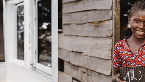 Girl outside classroom holding a blackboard with numbers
