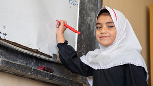 Girl attending class, writing on blackboard