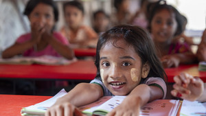 Girl smiling siting down and holding an open book