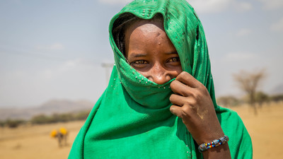Girl smiling and covering half of her face with a scarf