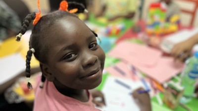 Sudanese refugee girl smiles in classroom in Egypt.