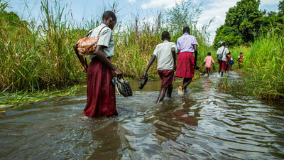 Students in South Sudan walk through flood water.