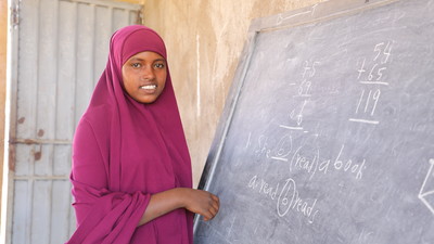 Girl stands in front of a blackboard in Ethiopia.