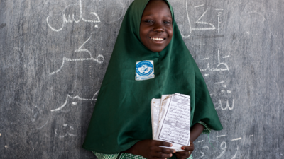 Happy Nigerian girl holding a book in a classroom