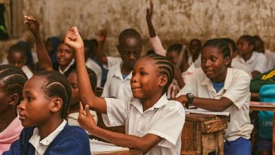 Girl in class in Kenya raises hand.