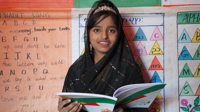 Rohingya girl reads from school book.