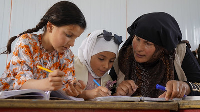 Teacher working with two students in Syria.