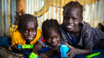 Children playing with didactic materials smiling and looking at the camera