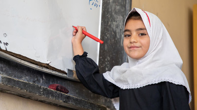 Girl attending class, writing on blackboard