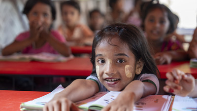 Girl smiling siting down and holding an open book