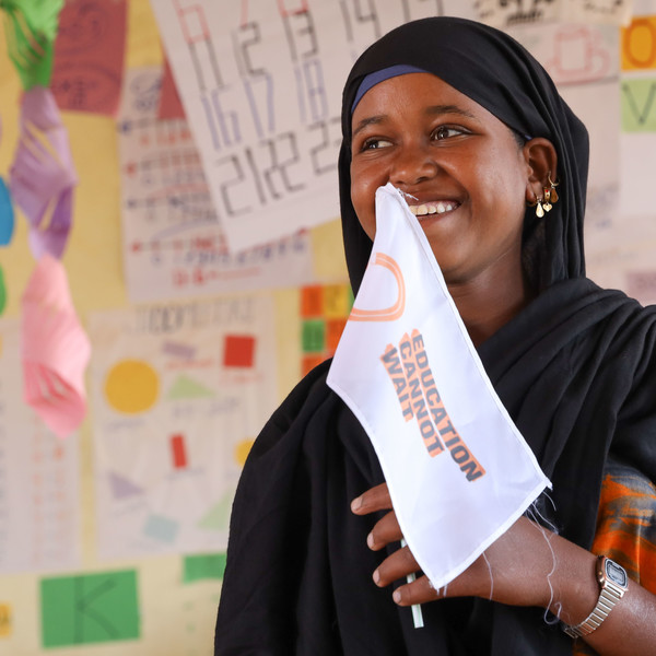 Girl in a classroom holding a flag with ECW's logo