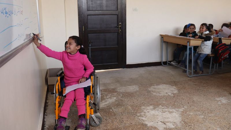 Hanaa, 8, who was paralysed by an exploding bomb and lost the use of her legs, solves a problem on a whiteboard in a classroom at a school in east Aleppo city, Syrian Arab Republic, February 2018. Hanaa's dream is to become a physiotherapist to help children like her. ©UNICEF/Al-Issa