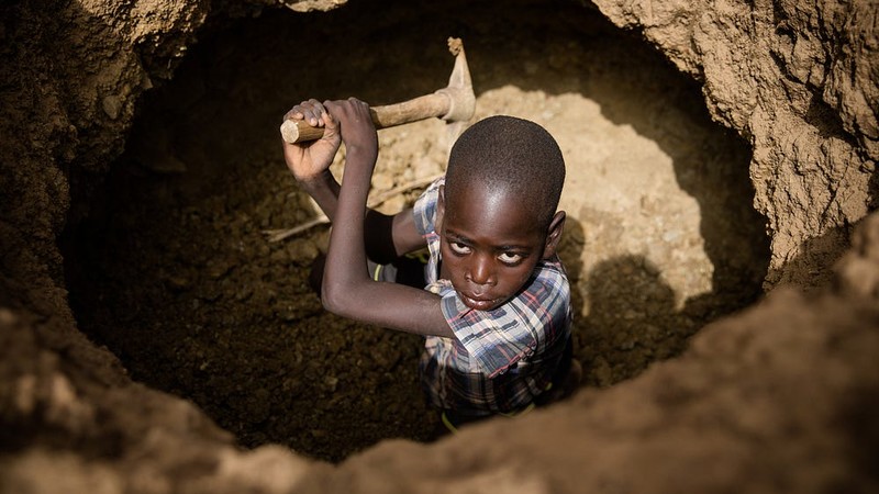 Young boy digging in a hole.