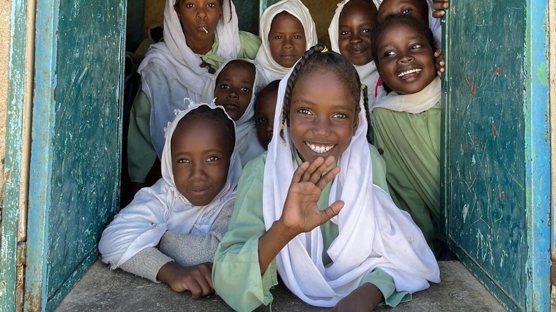 Girls inside a classroom smiling