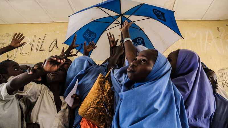 Students in a classroom in Nigeria hold up an umbrella.