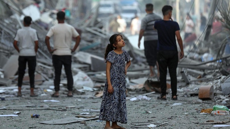 Palestinian child in the street amidst the wreckage of homes destroyed by airstrikes in the Gaza Strip