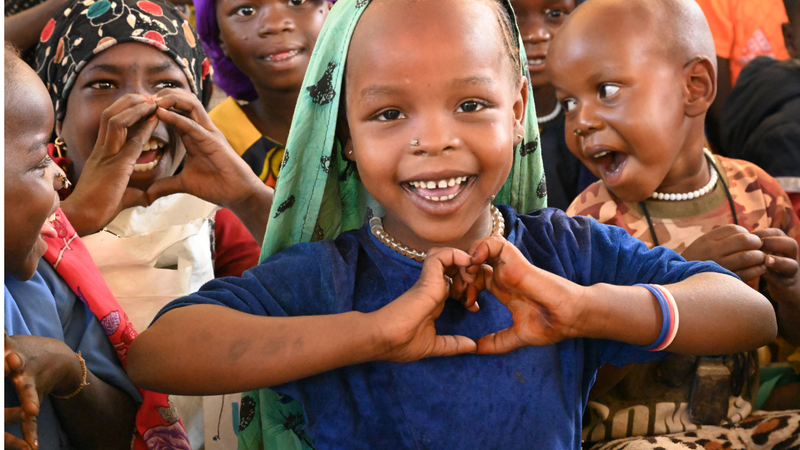 Girl in classroom making a heart shape with her hands