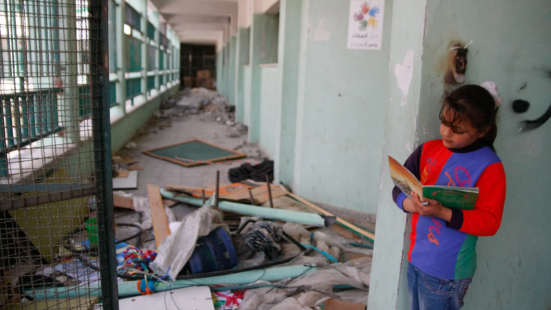Girl reads a book amidst rubble in Gaza