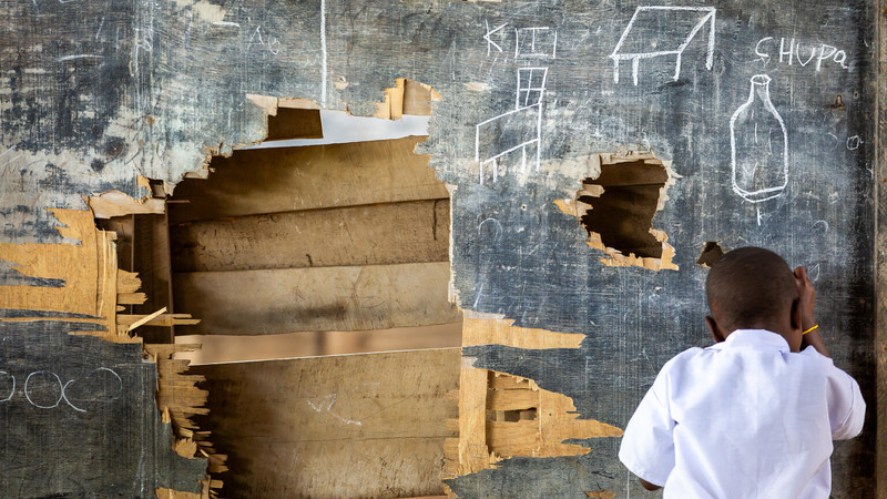 Children writing on an impacted blackboard