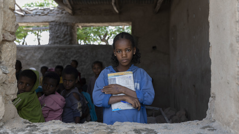 Girl inside a classroom holding a book
