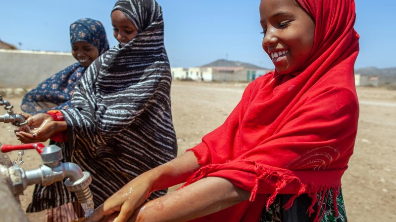 Girl smiling and washing her hands in a school in Africa
