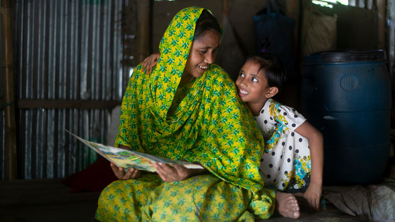 Mother reading a book to her daughter in Bangladesh