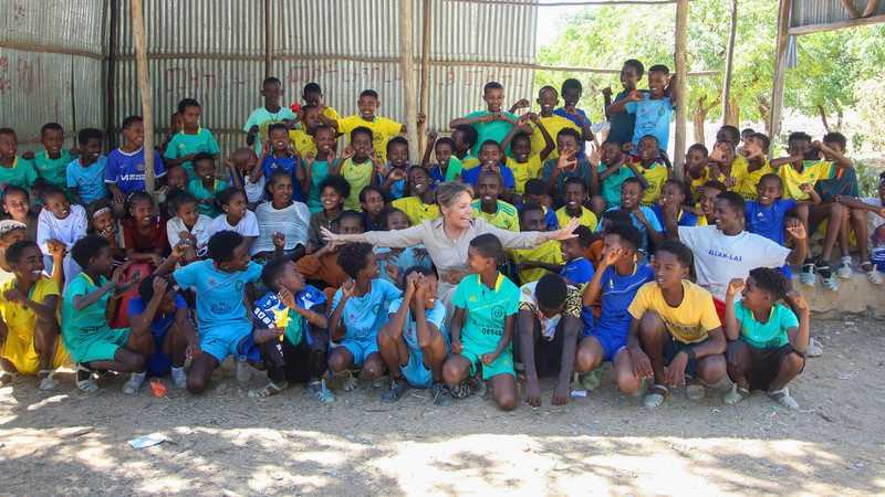 Group photo of Yasmine Sherif and children smiling at a school playground in Ethiopia