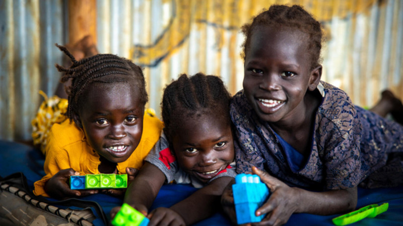 Children playing with didactic materials smiling and looking at the camera