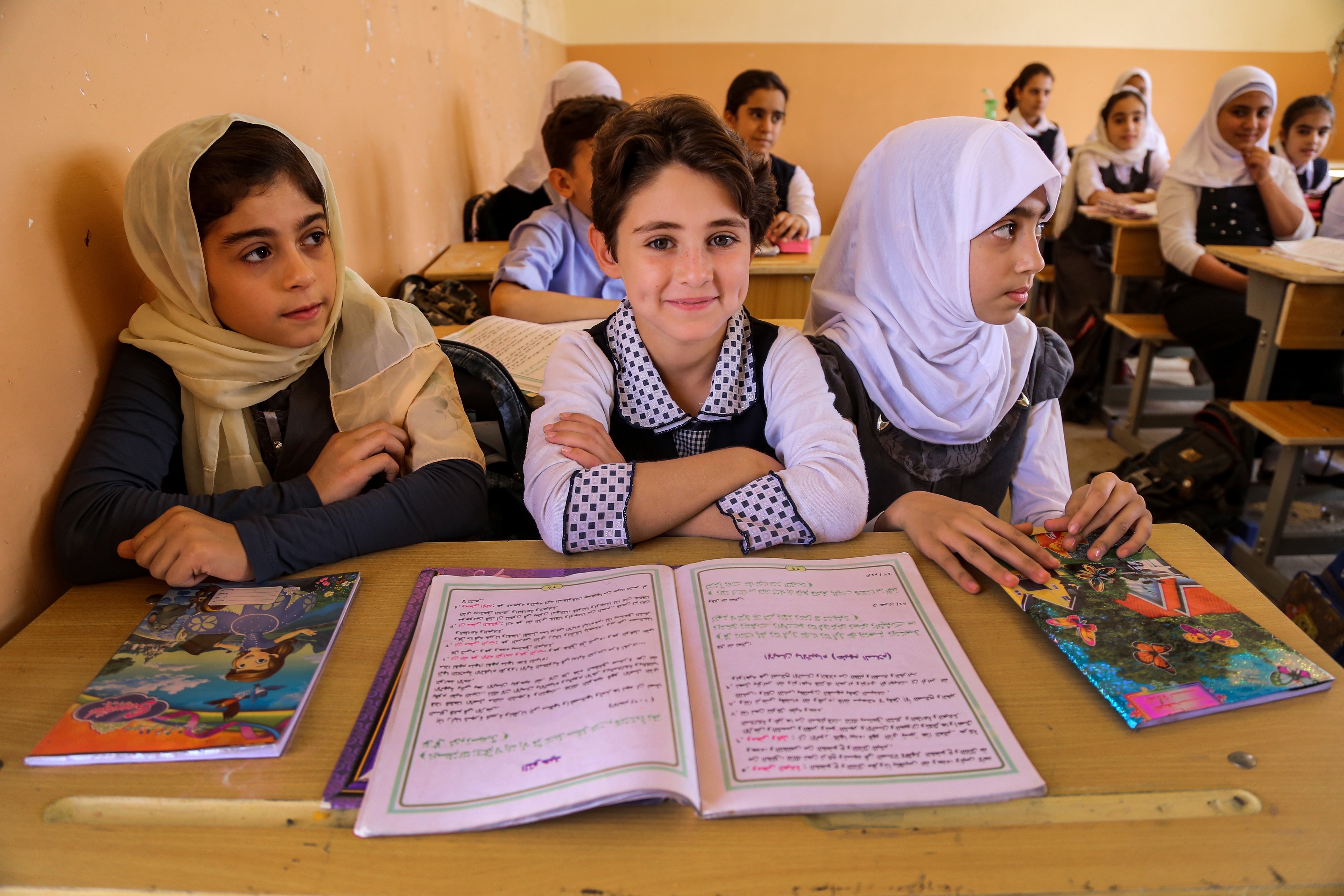 Girls attending class with notebooks and school supplies on their desk