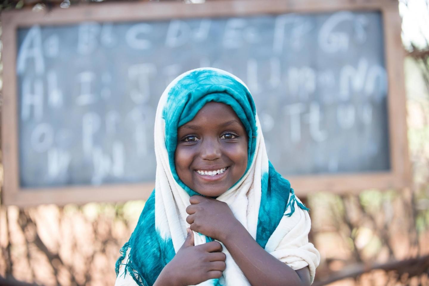 Girl smiling with a school blackboard behind her