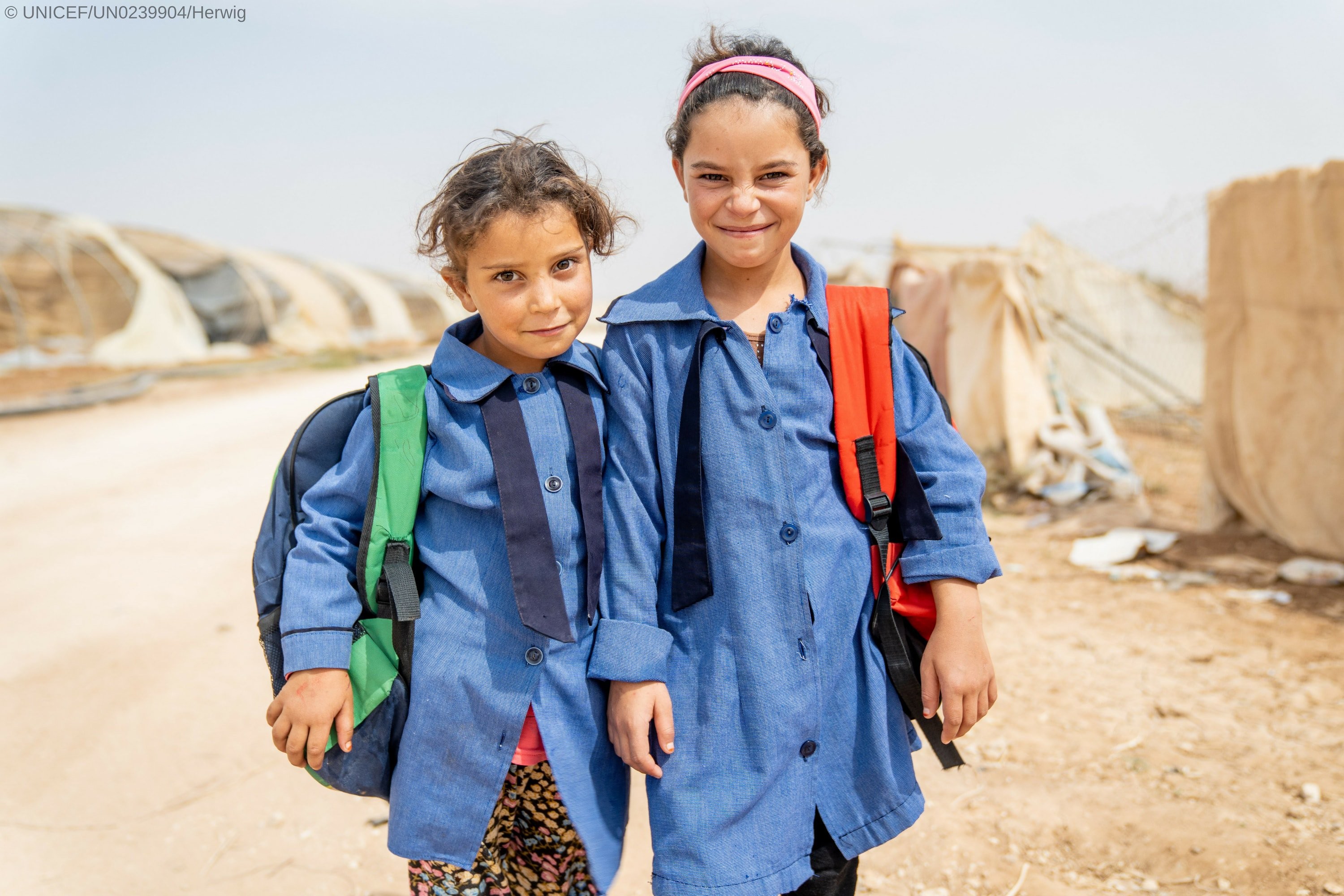 Two girls wearing their school uniforms smiling to the camera