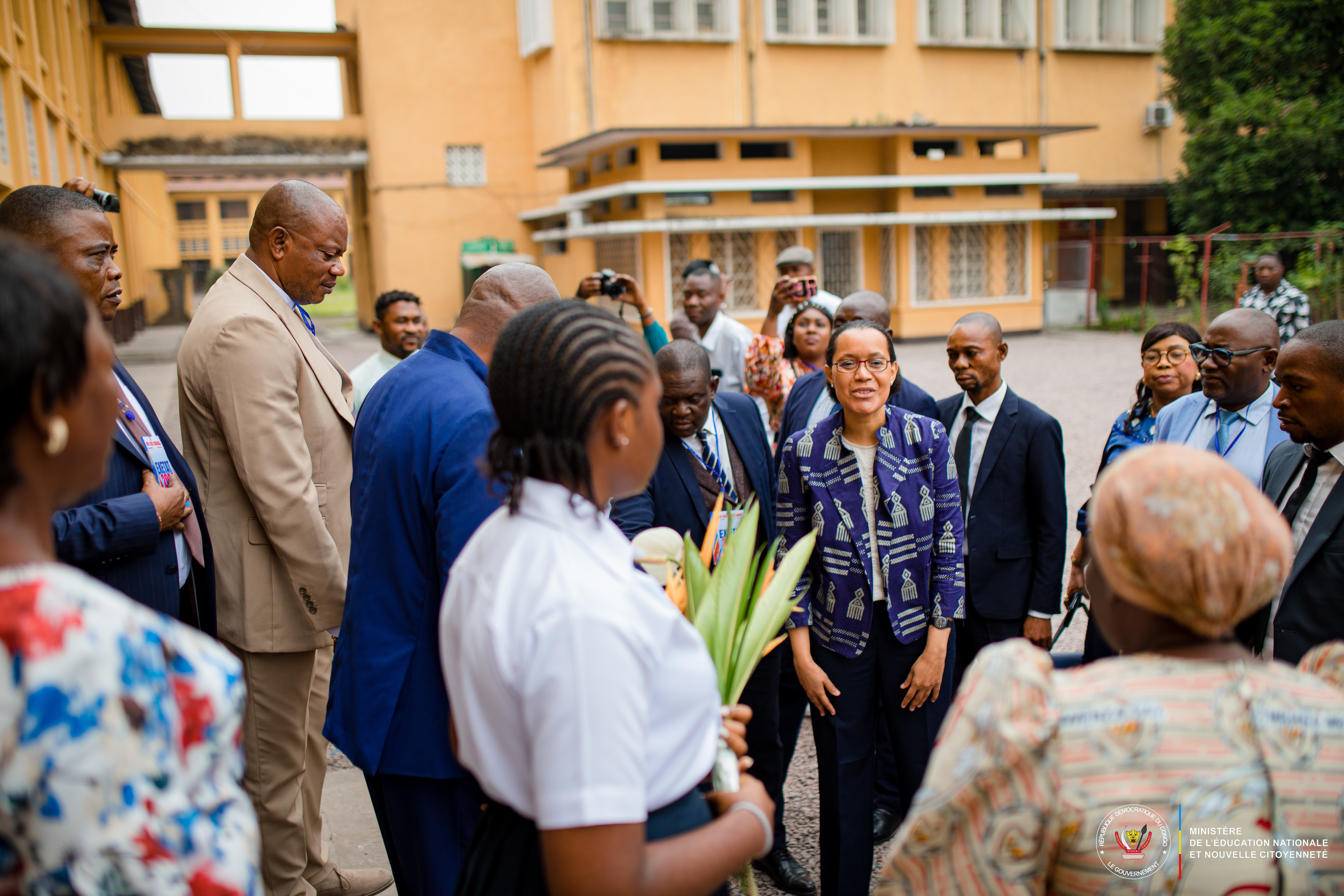 Raïssa Malu is Minister of State, Minister of National Education and New Citizenship for the Democratic Republic of the Congo with a group of people outside a building