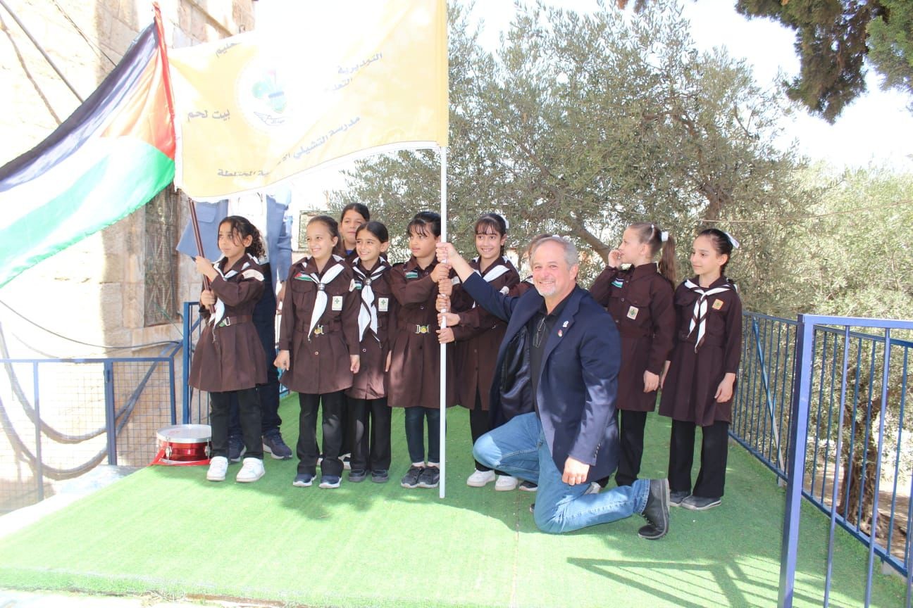 Dr. David Edwards with a group of children posing for a picture holding flags in Palestine